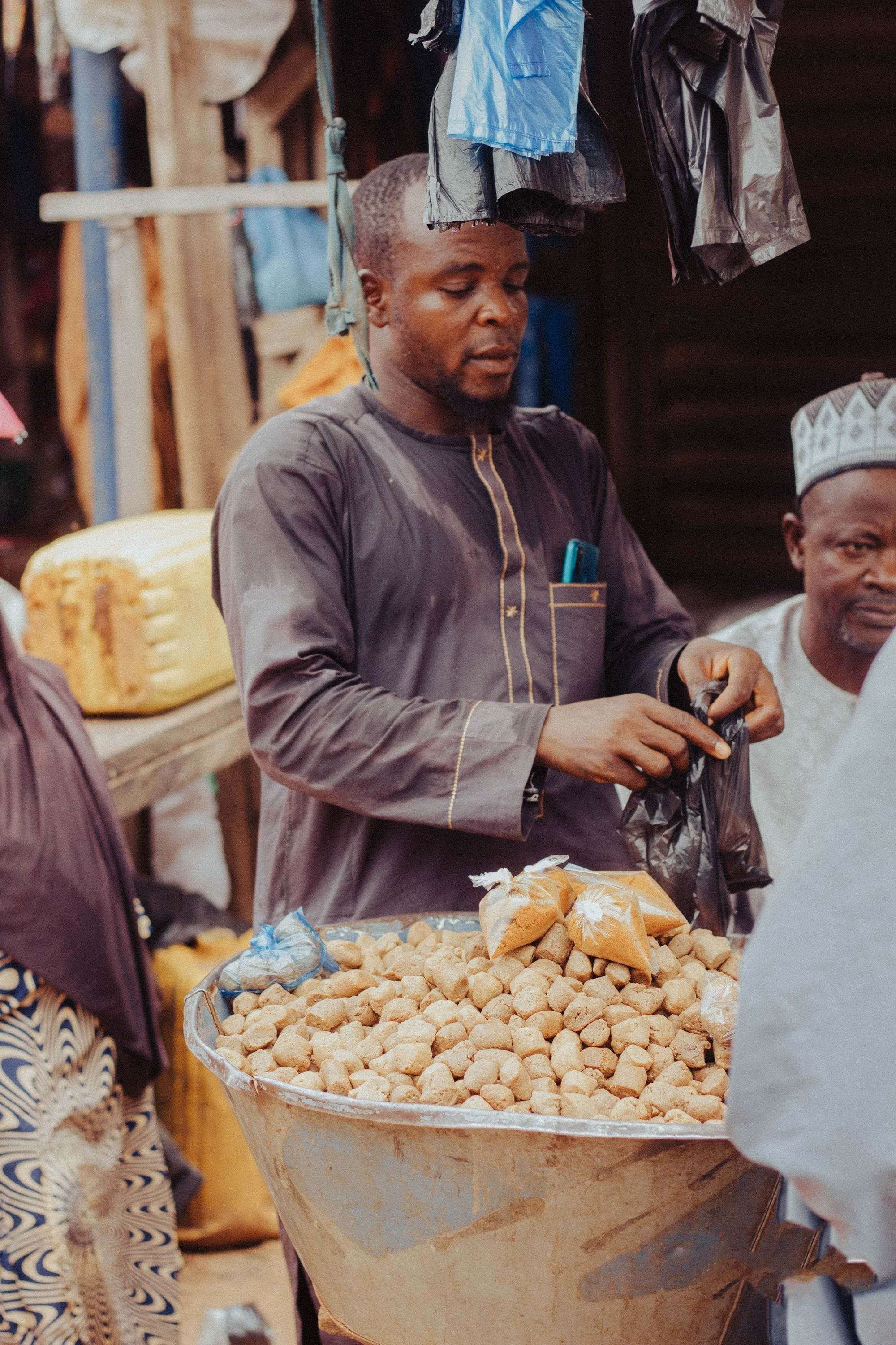 Un commerçant prépare un sachet devant son étal de cacahuètes sur un marché.